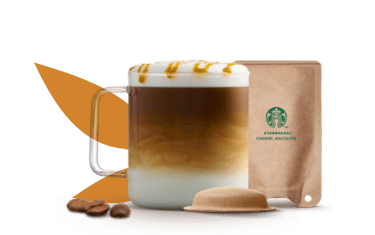 Taza con caramel macchiato junto a una cápsula y un sobre de papel