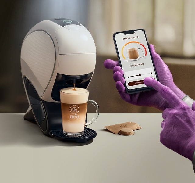 Una mano alienígena utilizando la aplicación NESCAFÉ Dolce Gusto para personalizar una bebida. Cafetera inteligente NEO Latte, pack de café y bebidas.